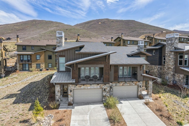 view of front of home with a mountain view, driveway, stone siding, board and batten siding, and an attached garage