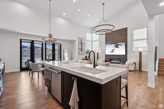 kitchen featuring a glass covered fireplace, a chandelier, dishwasher, light countertops, and a sink