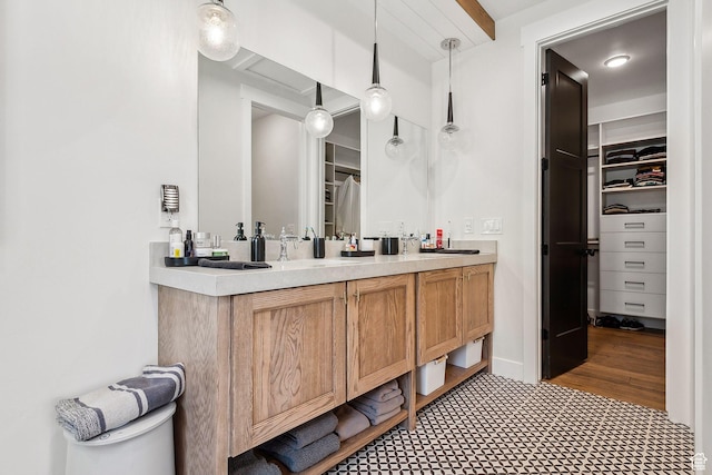 full bath featuring double vanity, a sink, and a walk in closet