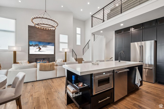 kitchen with light wood-type flooring, light countertops, an inviting chandelier, and appliances with stainless steel finishes