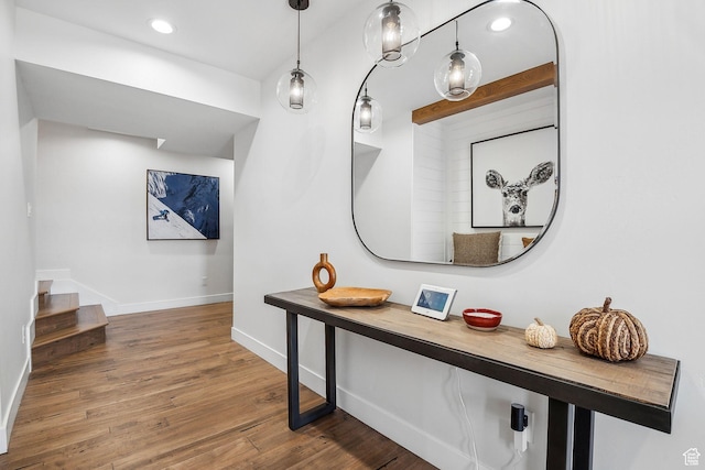 hall featuring wood finished floors, baseboards, stairs, and recessed lighting