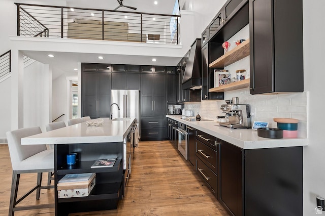 kitchen featuring high end refrigerator, light countertops, open shelves, and premium range hood