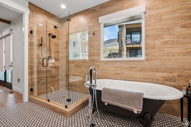 bathroom with a shower stall, a freestanding bath, and wood finished floors