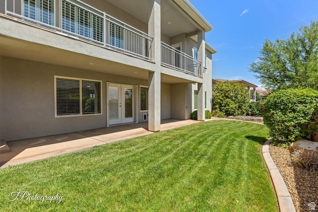 view of yard featuring a patio area, a balcony, and french doors
