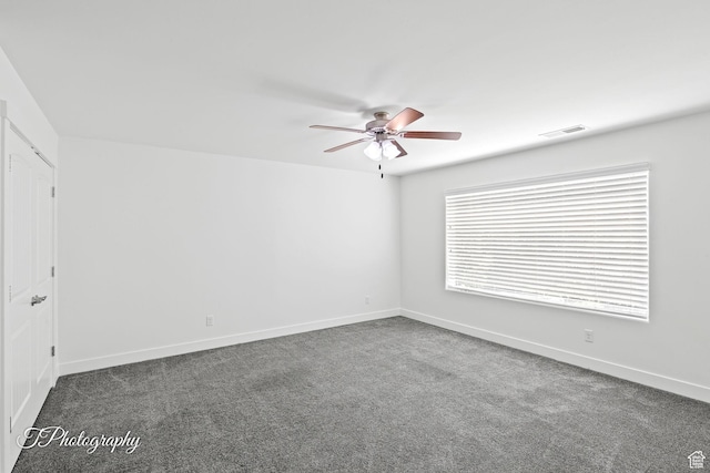 empty room with dark colored carpet, visible vents, baseboards, and ceiling fan