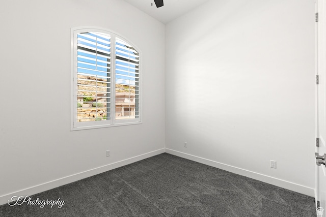 unfurnished room with dark carpet, baseboards, and a ceiling fan