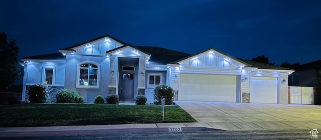 single story home with stucco siding, a lawn, stone siding, a garage, and concrete driveway
