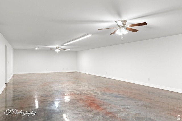 empty room featuring finished concrete flooring, baseboards, and ceiling fan