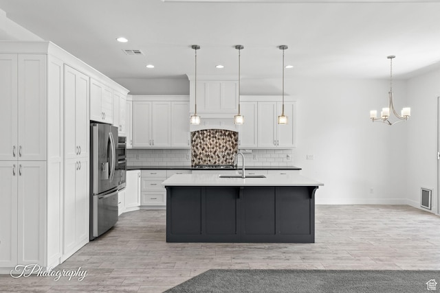 kitchen featuring an inviting chandelier, stainless steel fridge with ice dispenser, visible vents, a sink, and decorative backsplash