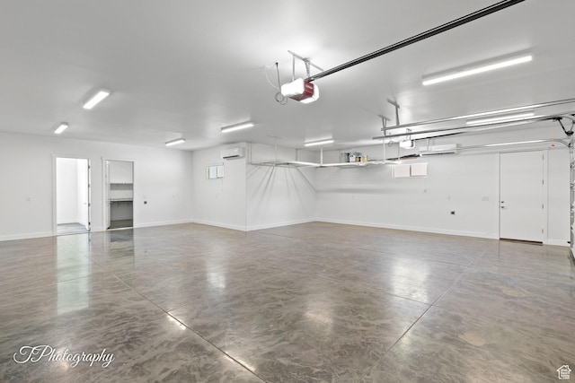 garage featuring a wall mounted air conditioner, baseboards, and a garage door opener