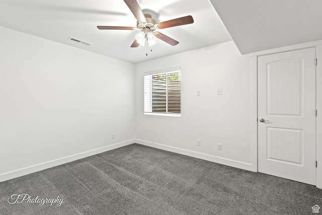 empty room with baseboards, ceiling fan, dark colored carpet, and visible vents