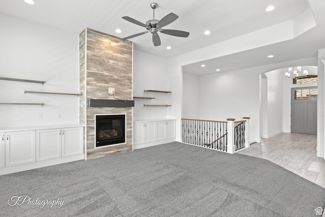 unfurnished living room featuring carpet floors, a tile fireplace, ceiling fan with notable chandelier, and recessed lighting