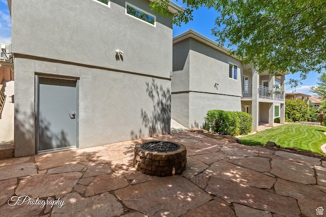 back of house with an outdoor fire pit, a patio, stucco siding, and a balcony