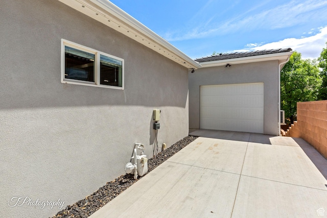 exterior space with driveway, stucco siding, a tile roof, and a garage