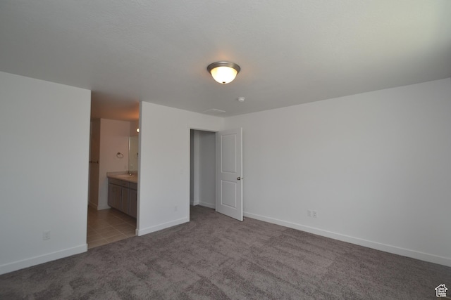 unfurnished bedroom featuring ensuite bath, baseboards, and carpet