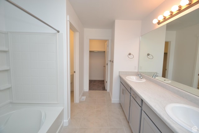 full bath featuring a bathing tub, double vanity, a sink, and tile patterned flooring