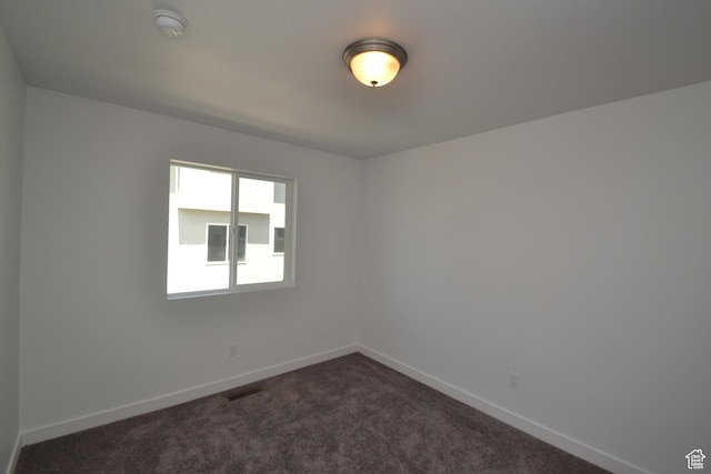 unfurnished room featuring dark carpet, baseboards, and visible vents