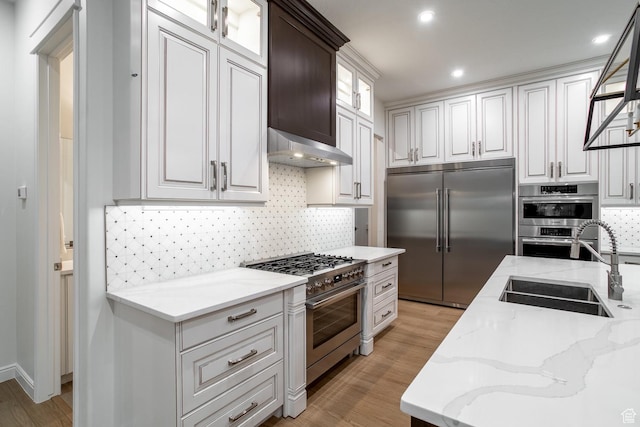 2889 E 1400 S, St George, UT 84790 - kitchen with wall chimney exhaust hood, glass insert cabinets, light wood-style flooring, a sink, and premium appliances