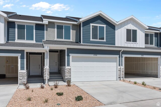 view of front of house featuring a garage, driveway, board and batten siding, and stone siding