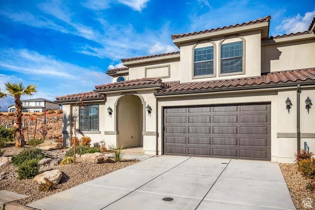 mediterranean / spanish-style house featuring a tiled roof, driveway, stucco siding, and an attached garage