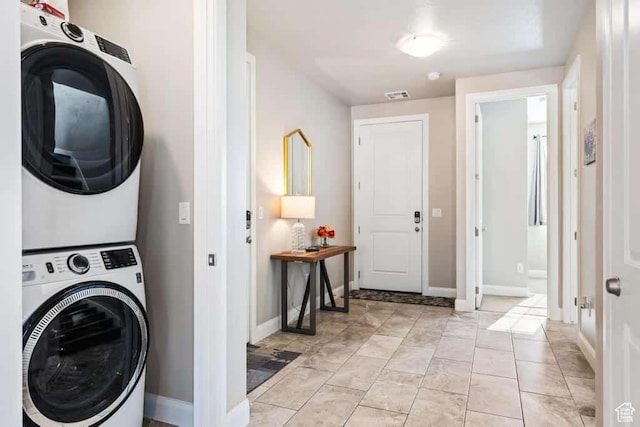 laundry area featuring visible vents, laundry area, stacked washer / drying machine, and baseboards
