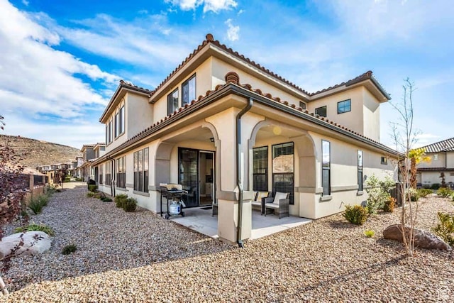 back of property with a patio, stucco siding, a tiled roof, and fence