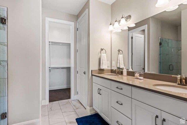 bathroom featuring a sink, baseboards, a shower stall, and marble finish floor