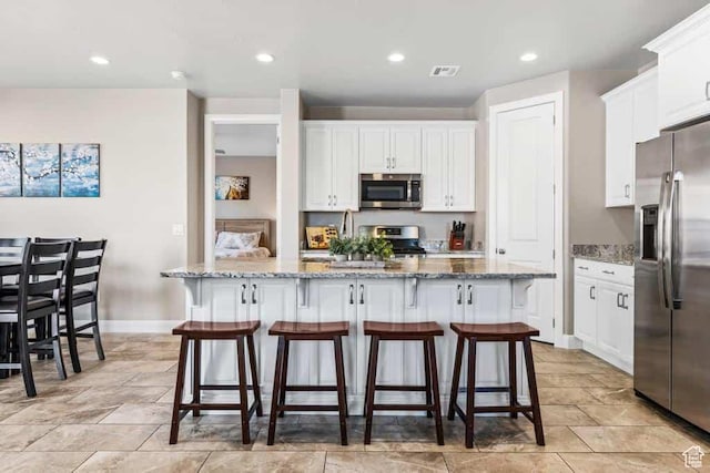 kitchen featuring visible vents, baseboards, appliances with stainless steel finishes, white cabinetry, and light stone counters