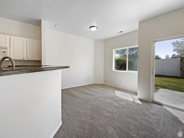 6647 W Merlot Way, West Jordan, UT 84081 - unfurnished living room with a sink, visible vents, baseboards, and light colored carpet