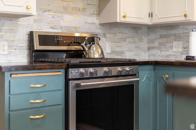 kitchen with tasteful backsplash, stainless steel gas range oven, dark countertops, white cabinets, and blue cabinets