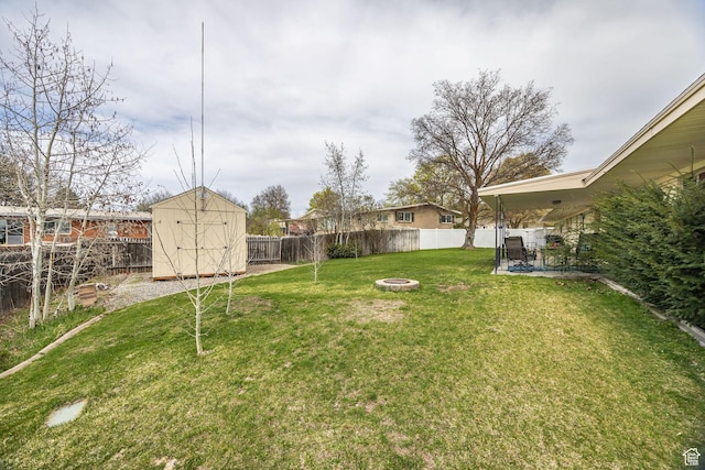 view of yard with a shed, a patio area, an outdoor fire pit, a fenced backyard, and an outdoor structure