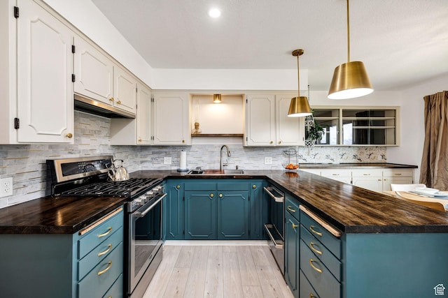 kitchen featuring light wood-style flooring, white cabinets, gas stove, a sink, and wooden counters