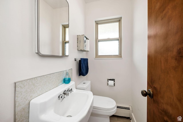bathroom with baseboards, a baseboard radiator, a sink, and toilet