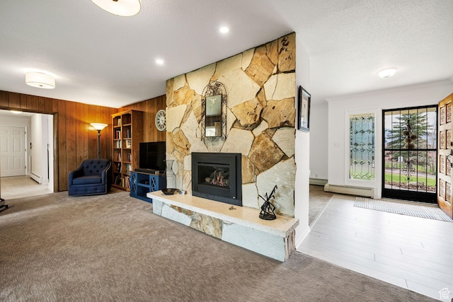 unfurnished living room with wood walls, a baseboard heating unit, a fireplace, and carpet
