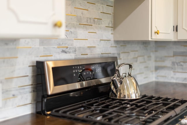 kitchen with decorative backsplash, white cabinetry, and stainless steel gas stove