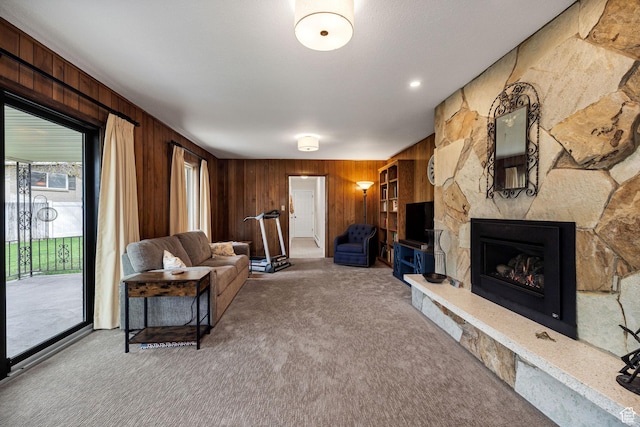carpeted living room featuring wooden walls and a stone fireplace