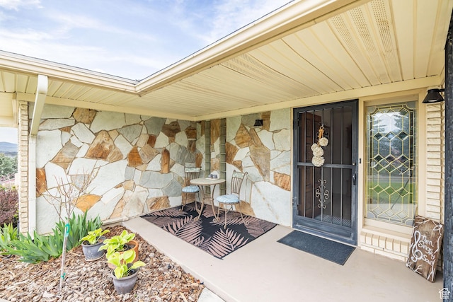 doorway to property featuring stone siding and covered porch