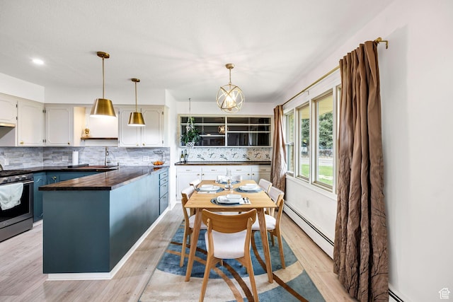 kitchen with tasteful backsplash, baseboard heating, gas stove, light wood-style flooring, and pendant lighting