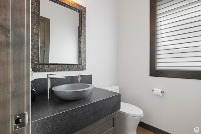 bathroom with vanity, baseboards, and toilet