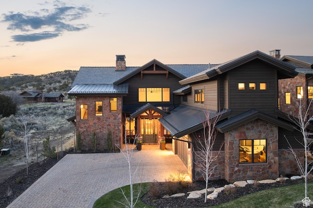 view of front of house with stone siding, driveway, and a chimney