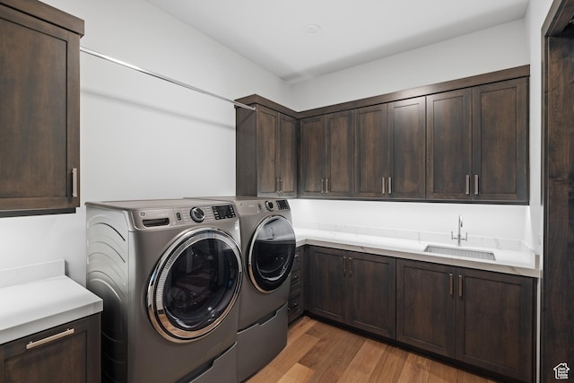 laundry area with a sink, light wood-style flooring, cabinet space, and washer and dryer