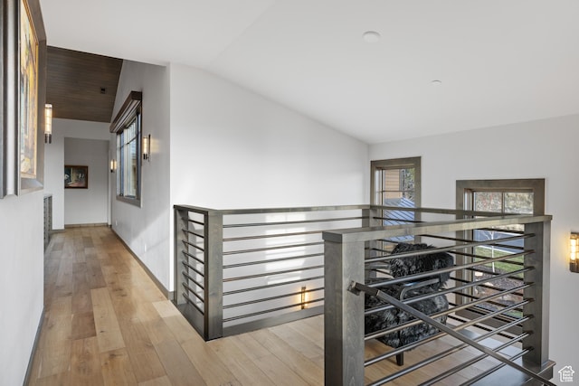 corridor featuring an upstairs landing, wood finished floors, and lofted ceiling
