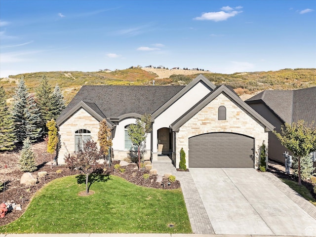 view of front of house featuring driveway, stone siding, a garage, and a front lawn