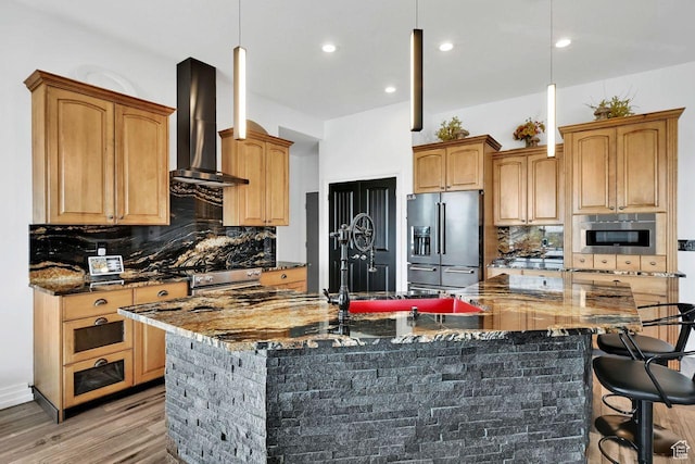 kitchen featuring light wood-style flooring, wall chimney range hood, a large island, decorative backsplash, and high end fridge