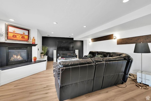 living area with a glass covered fireplace, recessed lighting, and light wood-type flooring