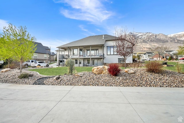 view of front facade featuring a residential view, a balcony, a mountain view, and stucco siding