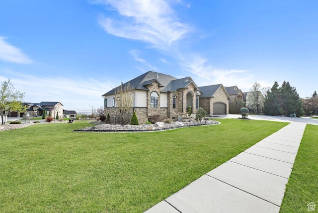 french country home with concrete driveway, a garage, stone siding, and a front lawn
