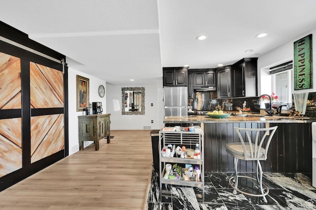 kitchen featuring freestanding refrigerator, a kitchen breakfast bar, light wood-style floors, a peninsula, and recessed lighting