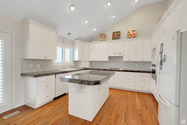 8046 W Harker Canyon Dr, Magna, UT 84044 - kitchen with under cabinet range hood, tasteful backsplash, visible vents, white cabinetry, and white appliances