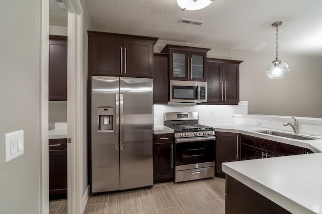 kitchen with dark brown cabinetry, visible vents, light countertops, a sink, and stainless steel appliances